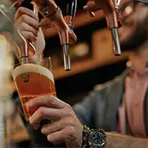 Person pouring craft beer at outdoor entertainment gathering in luxury backyard setting