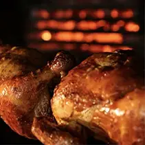 Rotisserie grill with golden-brown meat cooking over flames for backyard entertainment