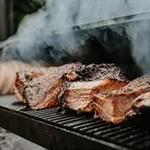 Smoker grill cooking steaks for luxury backyard entertainment and outdoor living spaces