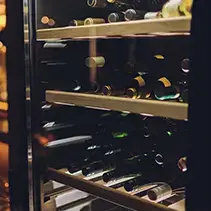 Wine fridge with multiple shelves displaying bottles in luxury outdoor entertainment space
