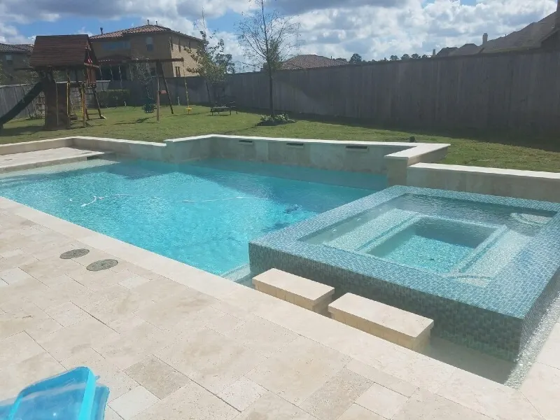 Geometric luxury backyard pool with glass tile spa and water feature in Woodlands