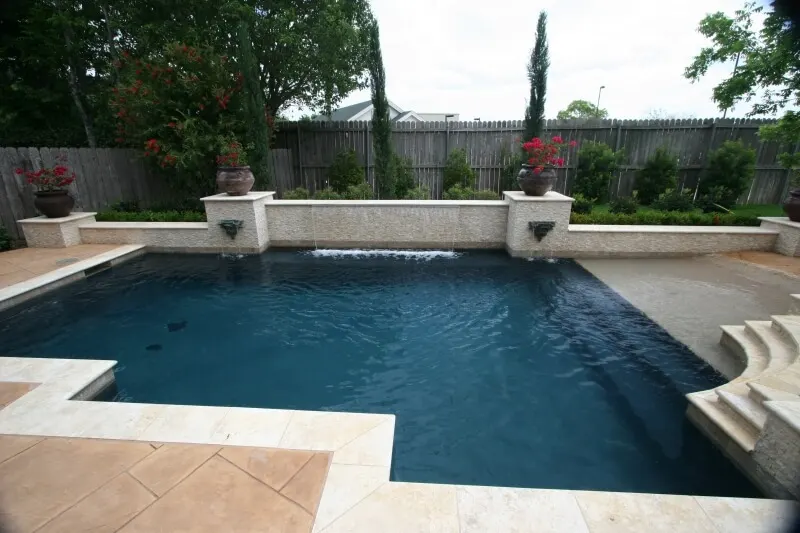 Geometric luxury backyard pool with stone water features and spa in Woodlands custom pool design