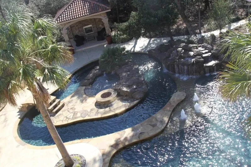Luxury backyard pool with lazy river, spa, waterfall features and outdoor cabana in Woodlands