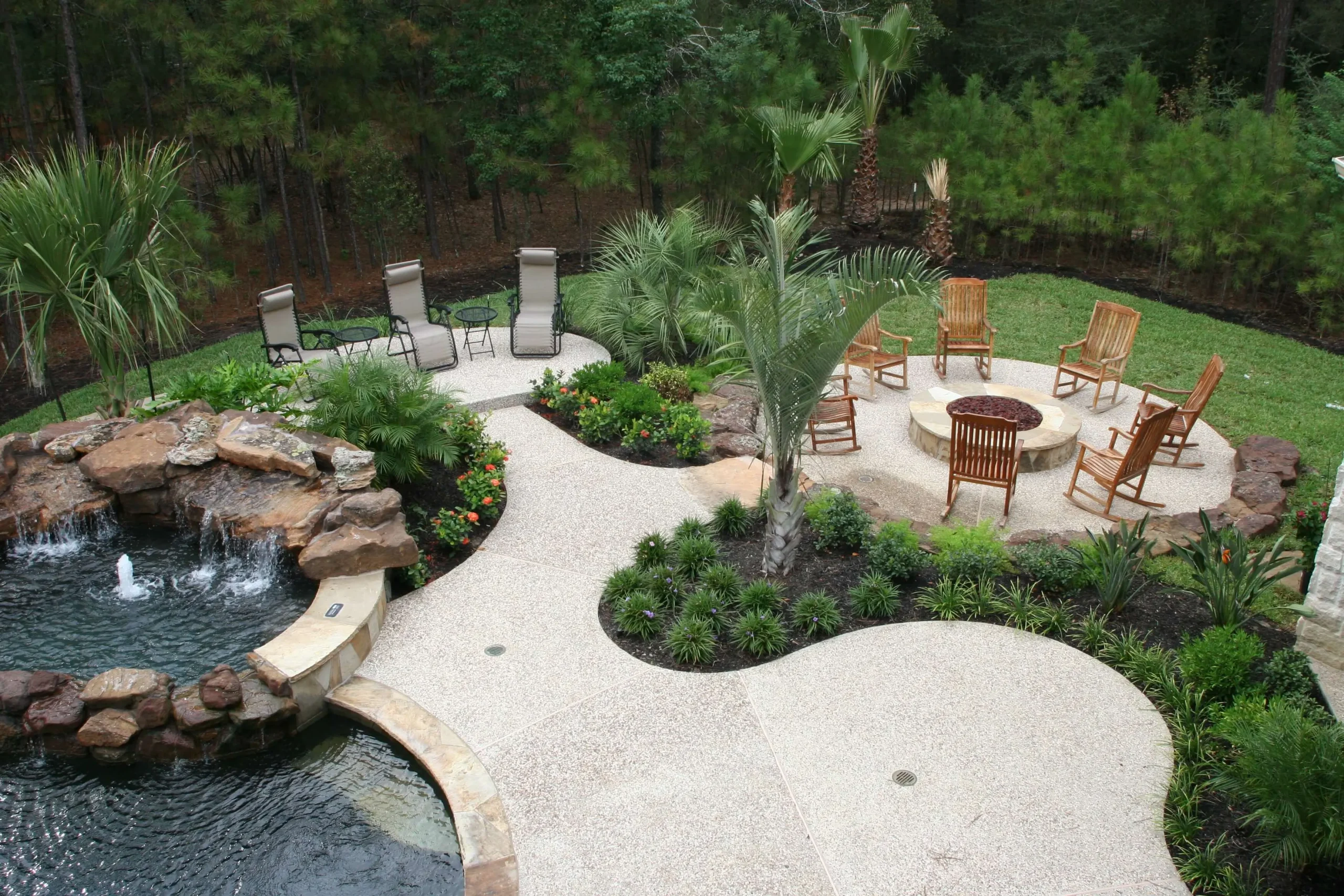 Luxury backyard pool with spa, fountain, fire pit, and outdoor living patio spaces surrounded by landscaping