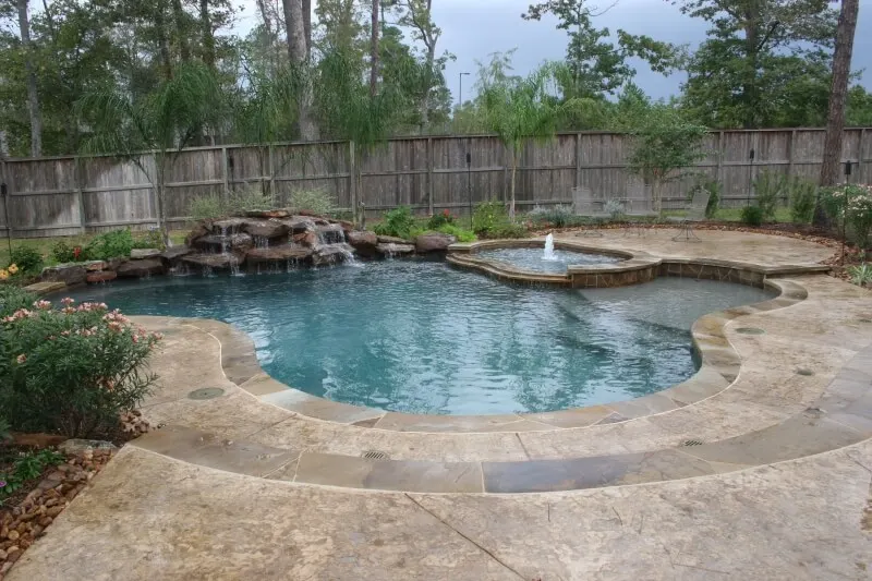 Luxury backyard pool with natural stone waterfall and spa in custom outdoor living space