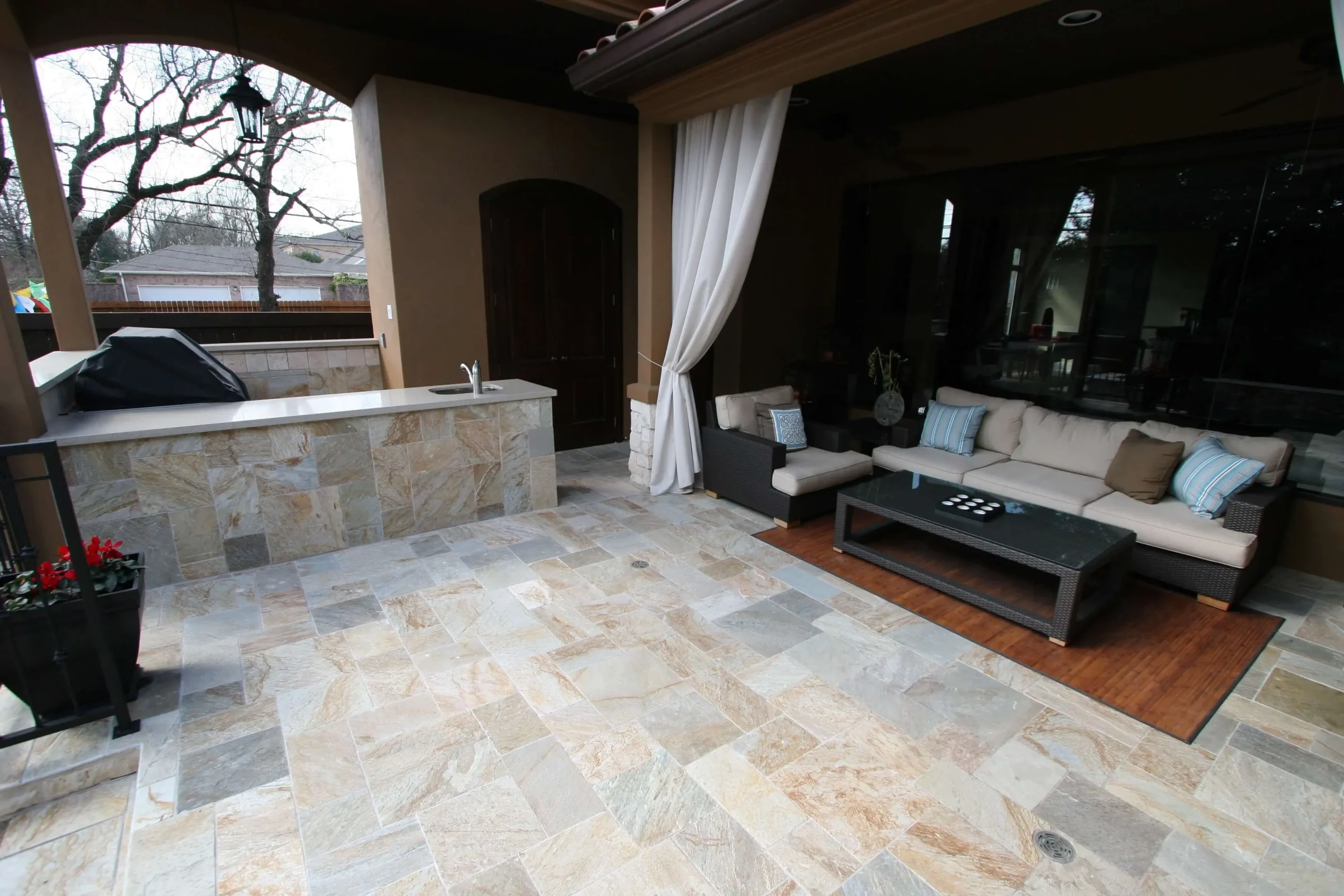 Luxury outdoor kitchen and patio with stone counters, seating area, and integrated pool design for backyard entertainment