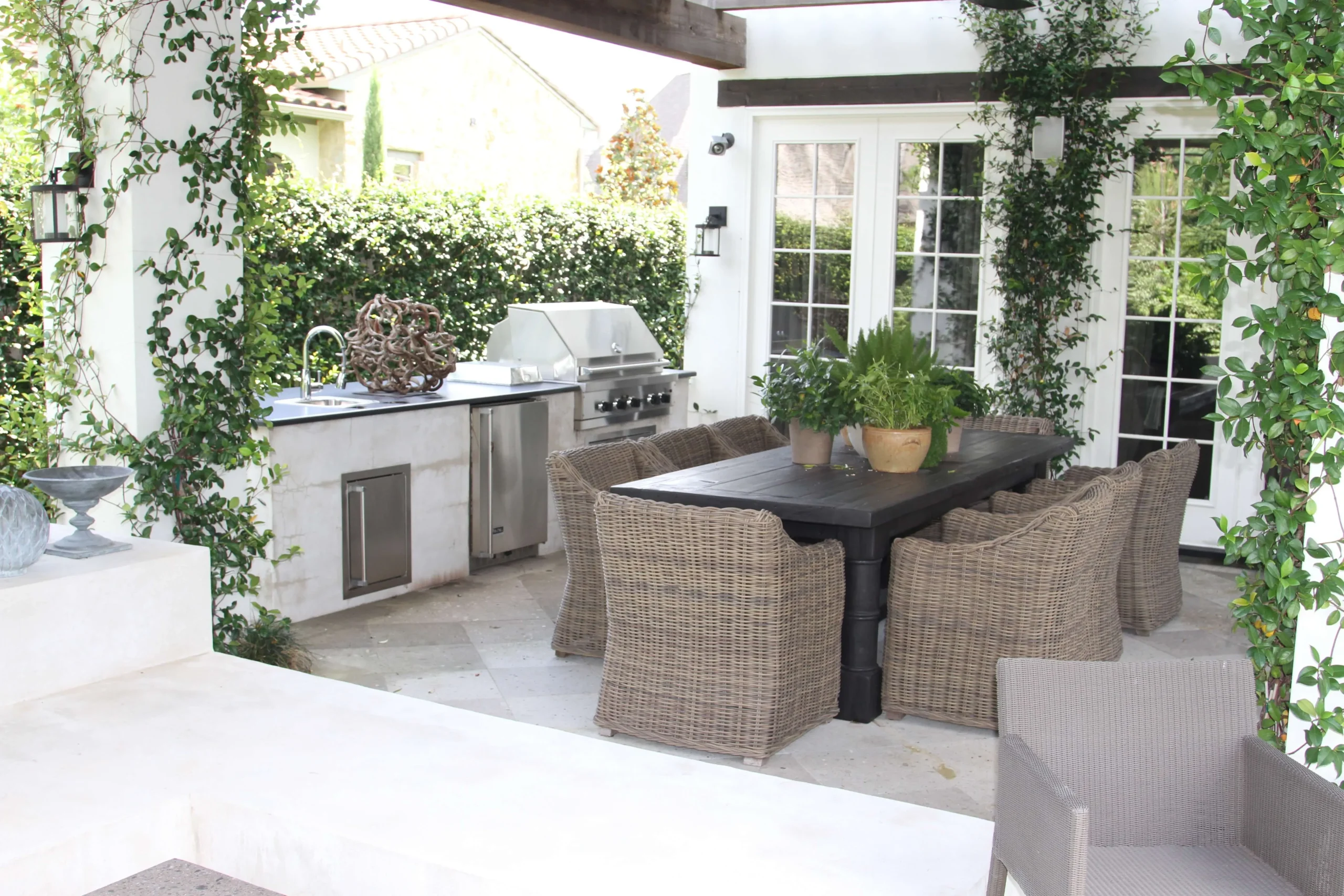 Luxury outdoor kitchen and dining patio with wicker seating and stainless steel grill