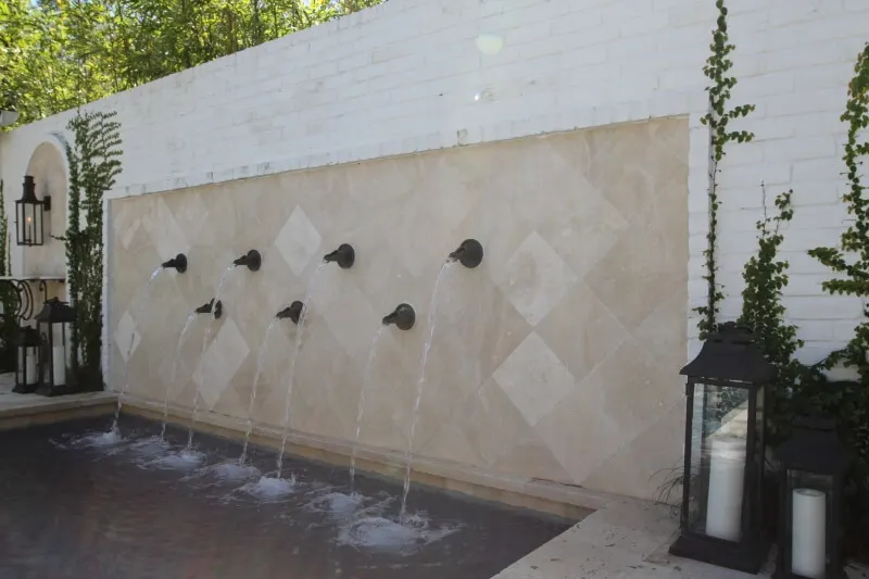Custom luxury pool fountain wall with multiple water features in elegant outdoor living space