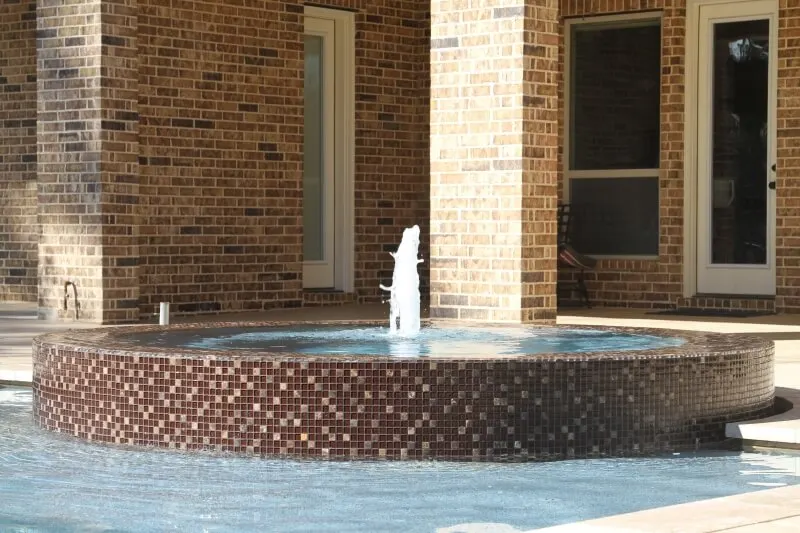 Luxury backyard spa with glass tile fountain and custom pool design by professional contractor