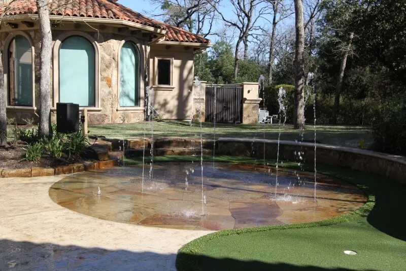 Luxury backyard splash pad and pool patio with fountain feature and outdoor entertainment space