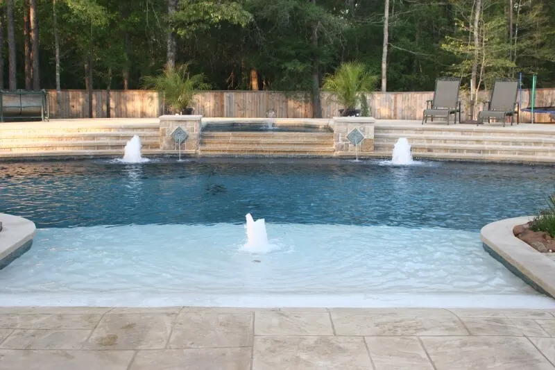 Luxury backyard pool with water features, spa, and outdoor patio entertainment space